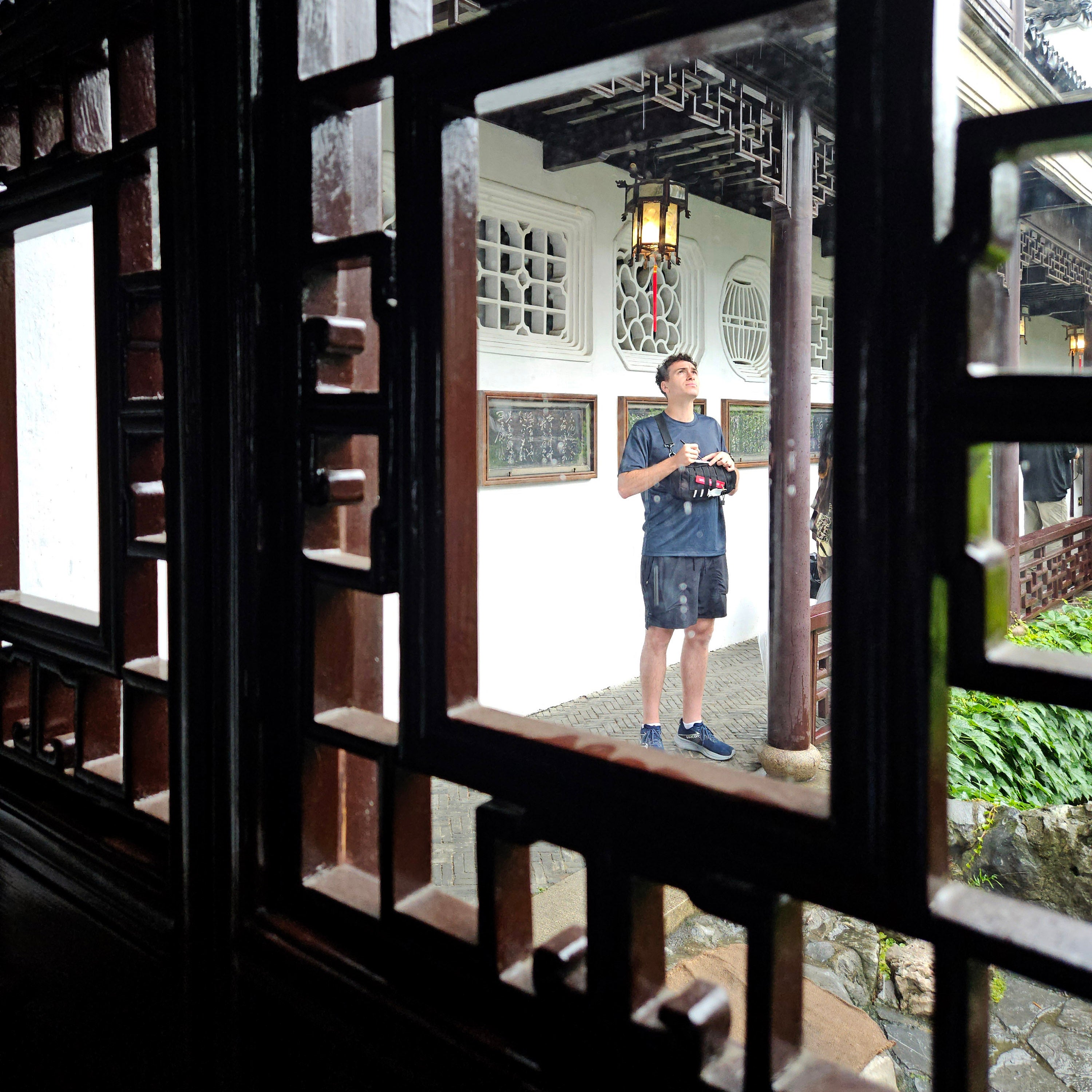 Man standing under a pavilion in a traditional Chinese garden