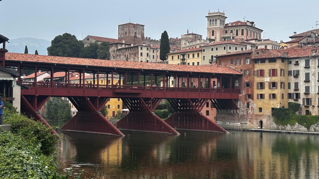 covered wooden bridge spanning a river in an Italian town