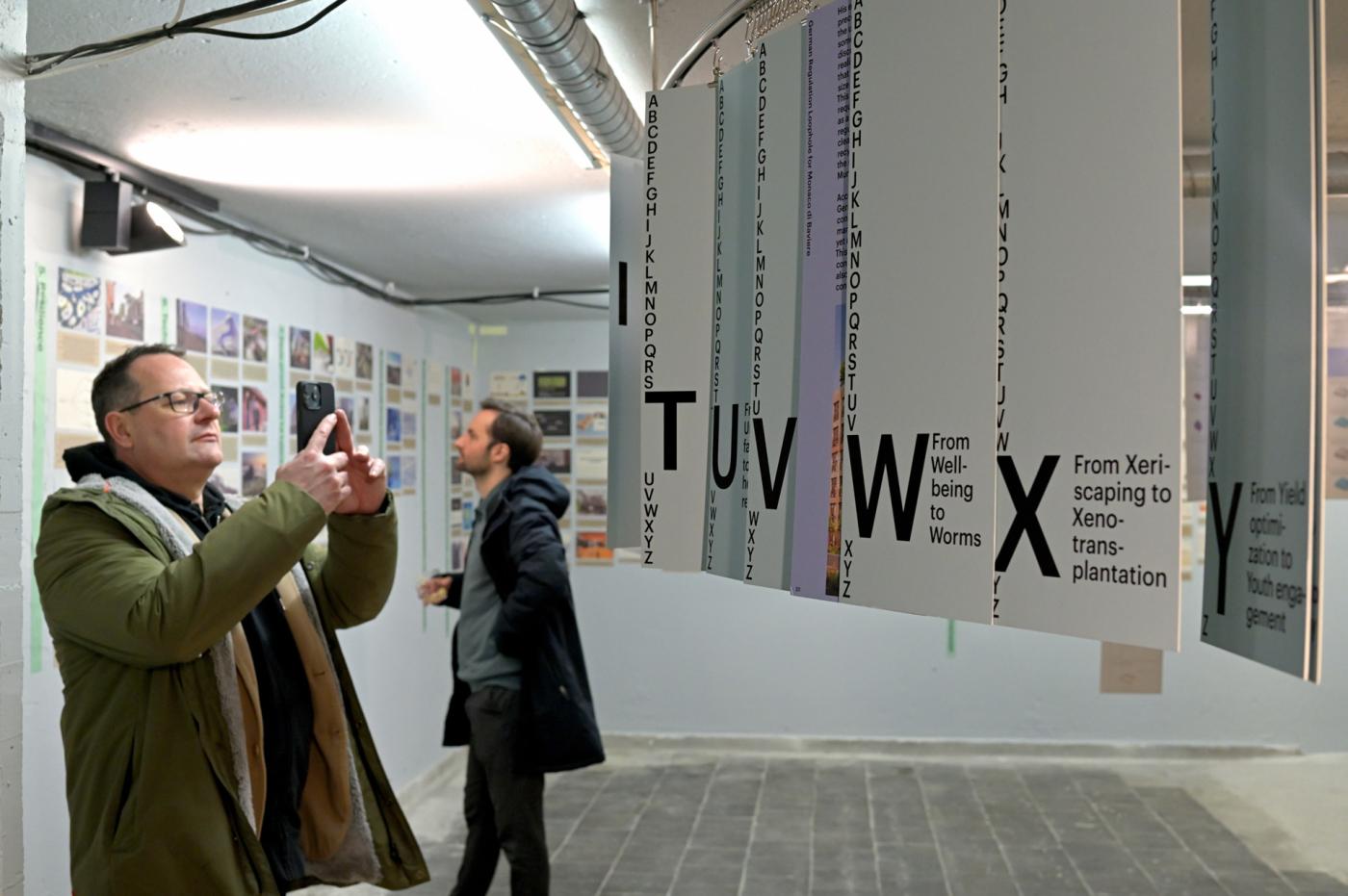 Man taking a photograph of panels hanging in interior art installation